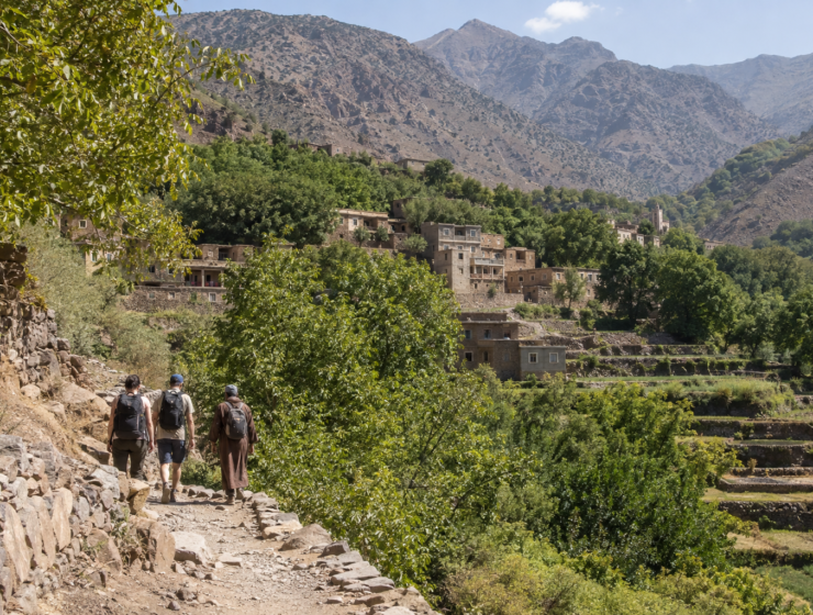 Travelers walking toward a mountain village in Morocco’s High Atlas